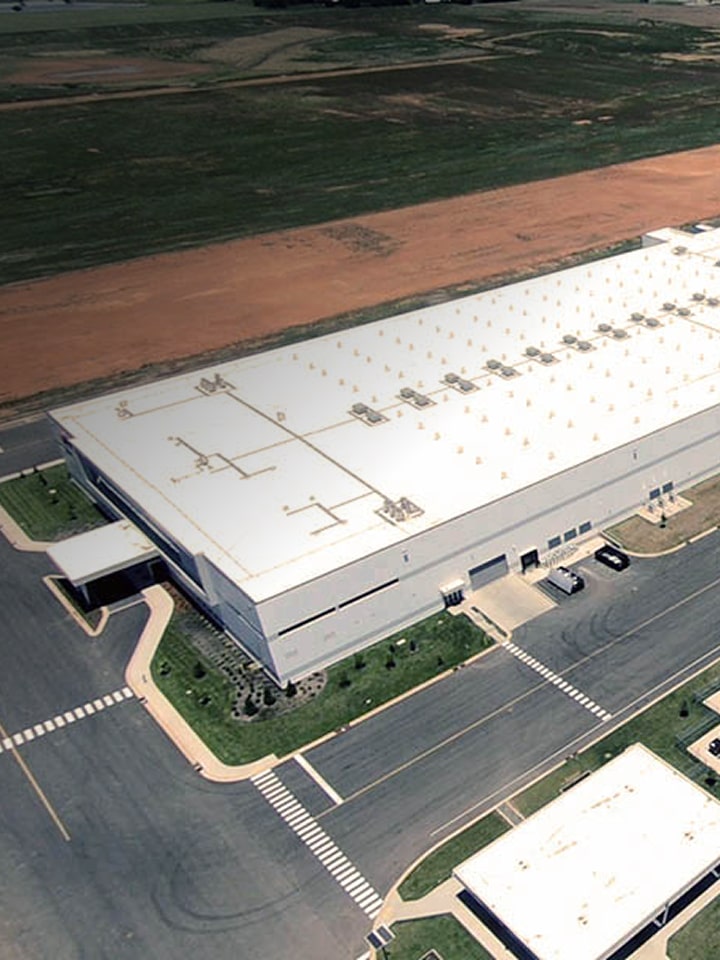 Stacks of large steel coils stored in an industrial warehouse, showcasing durable metal materials for manufacturing.