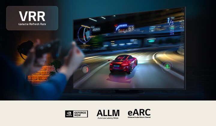 Tangan memegang pengontrol game di depan layar yang menampilkan permainan balap mobil. Logo VRR berada di pojok kiri atas. Logo Nvidia GeForce Now dan sertifikasi terkait lainnya terlihat.