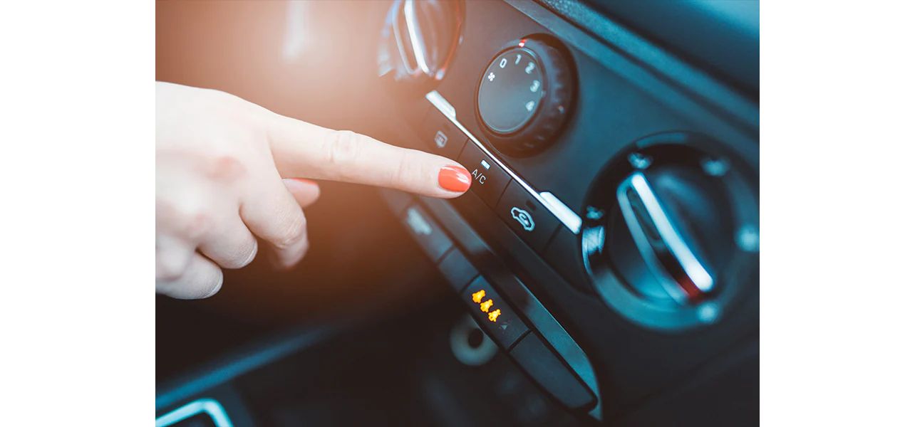 A person turning on the airconditioner button in a car.