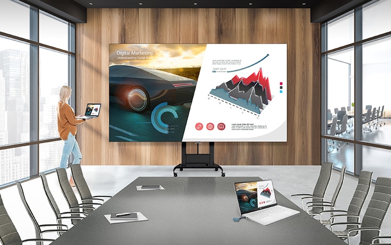 LAEC dipasang pada motorized stand pada ruang konferensi. Seorang pengguna sedang membagikan layar laptopnya ke layar LAEC menggunakan LG One:Quick Share.