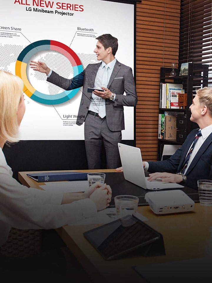 LG Minibeam projector supports mobile business presentations as a professional team engages in a meeting around a table inside a modern office