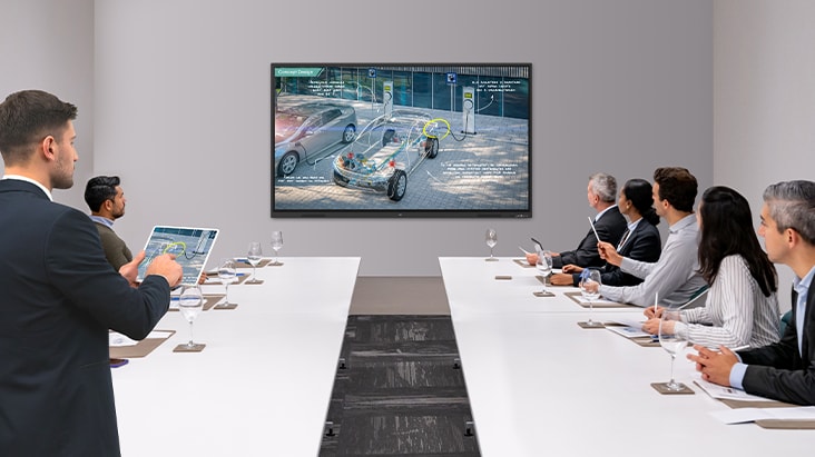 A presentation is underway in the meeting room equipped with an interactive smart board, with the presenter seamlessly controlling his materials via wireless screen sharing on his tablet.