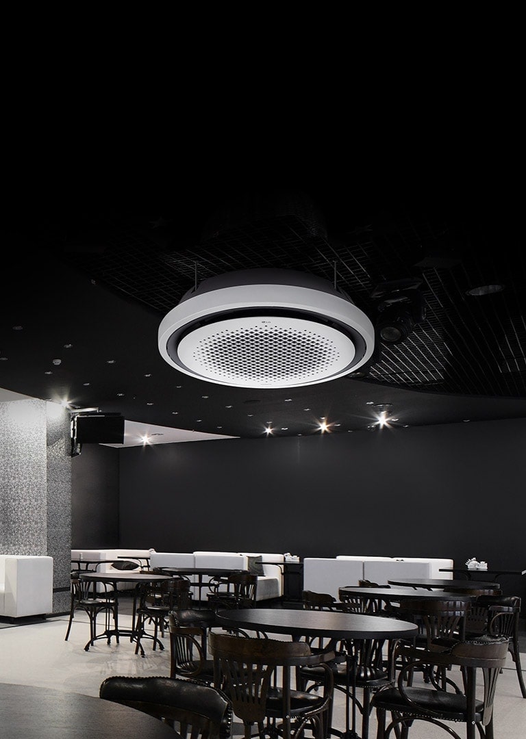 Black and white tone dining area with tables, chairs, and a sofa displayed. LG Round Cassette mounted on the ceiling.