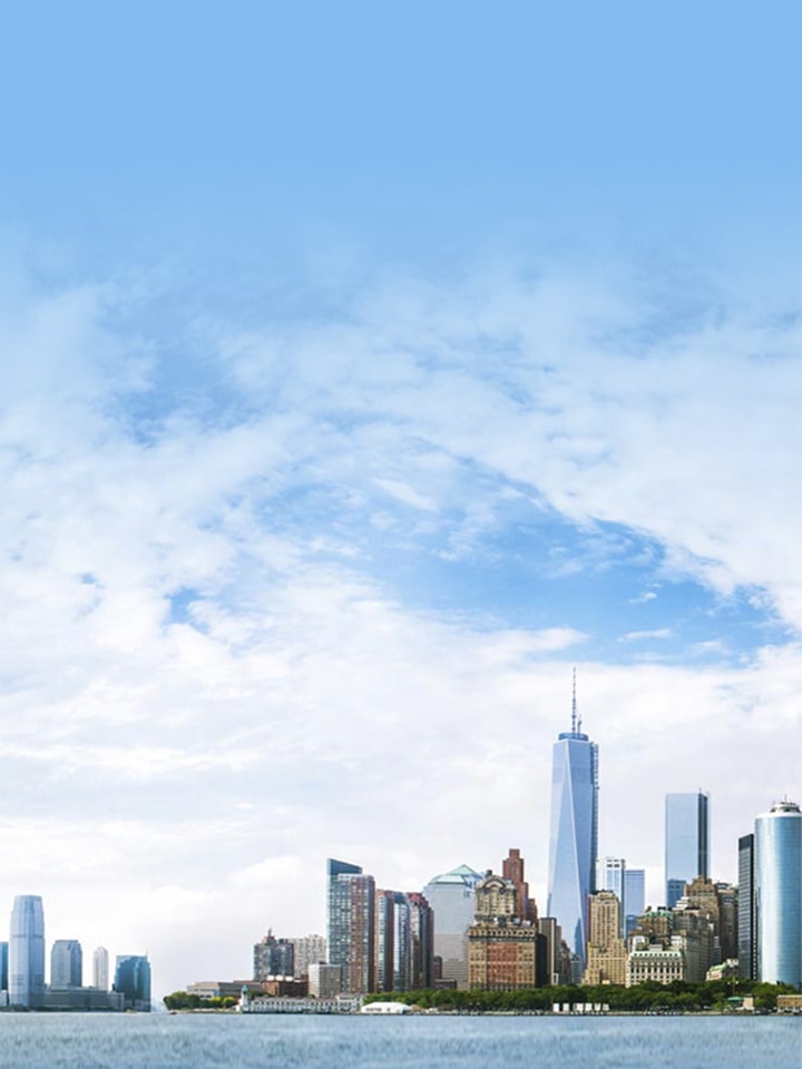 Panoramic view of a modern city skyline along the waterfront under a bright blue sky