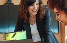 طالب ومعلمه يبتسمان أثناء العمل معًا على جهاز كمبيوتر محمول.