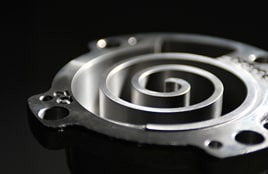 منظر عن قرب لمكون ضاغط حلزوني معدني ذو سطح أملس مصقول على خلفية داكنة.