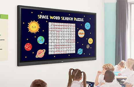 مشهد في الفصل الدراسي مع أطفال جالسين على مقاعدهم يشاهدون شاشة كبيرة تعرض "لغز البحث عن الكلمات في الفضاء" مع كواكب ونجوم حول شبكة اللغز.