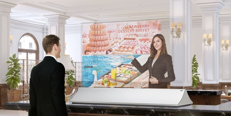 A man is getting information through the Transparent OLED screen showing photos of the dessert menu.