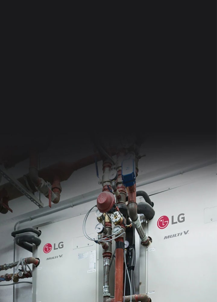 ในห้องเครื่อง มีท่อสีดำและสีแดงที่ซับซ้อนทอดยาวไปรอบๆ ชุดอุปกรณ์ LG Multi V สองชุดอุปกรณ์ที่ติดตั้งอยู่บนผนังด้านข้าง