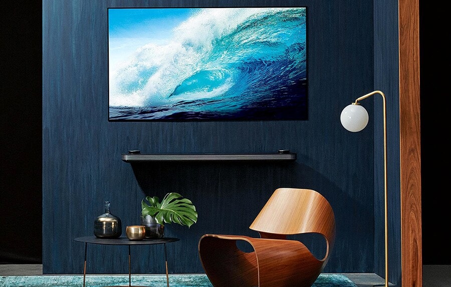 overall view of lg signature oled tv w hung on the blue wall with some furniture displayed