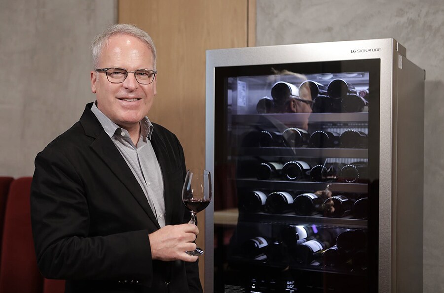 James Suckling is standing next to LG SIGNATURE Wine Cellar.