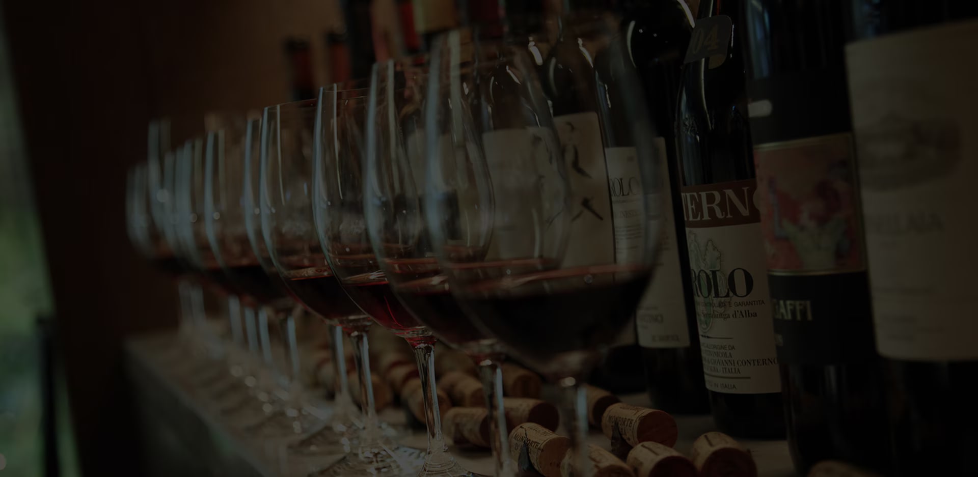 There are a lots of wines and glasses on the bar table.