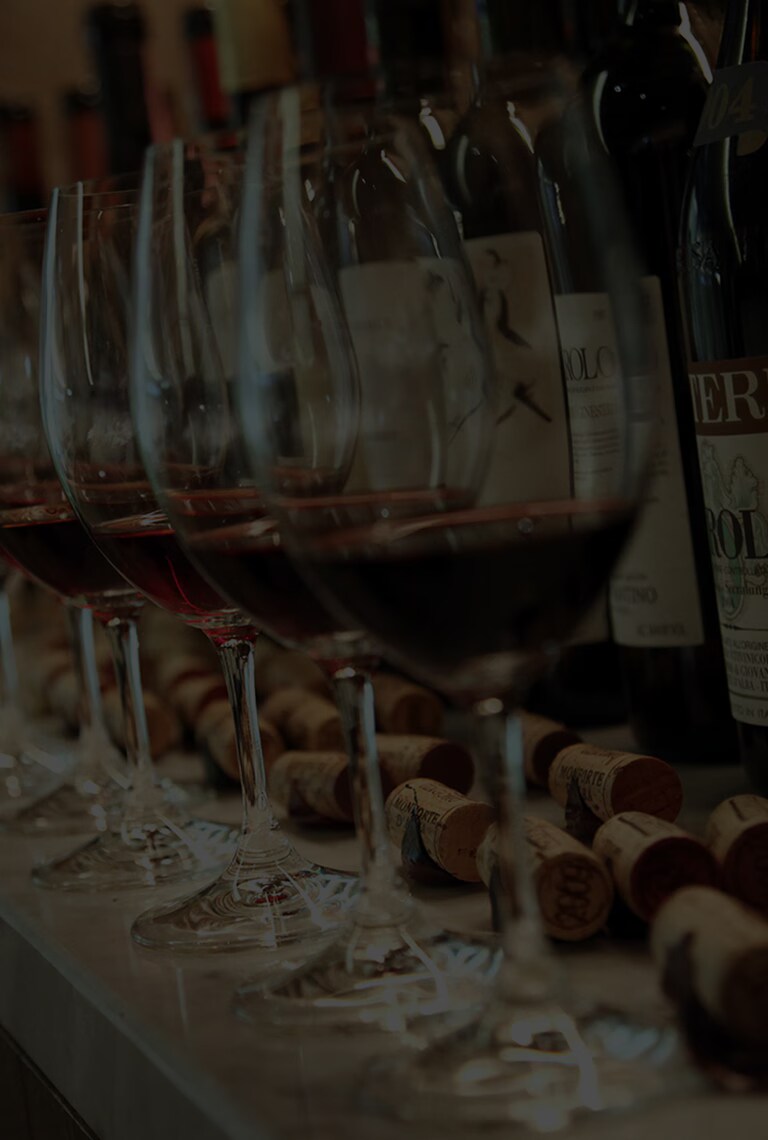 There are a lots of wines and glasses on the bar table.