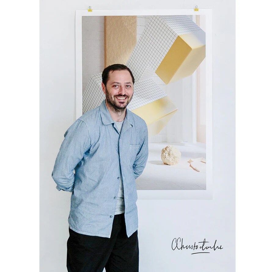 creator alexis christodoulou is standing with smile infront of his art work hung on the wall