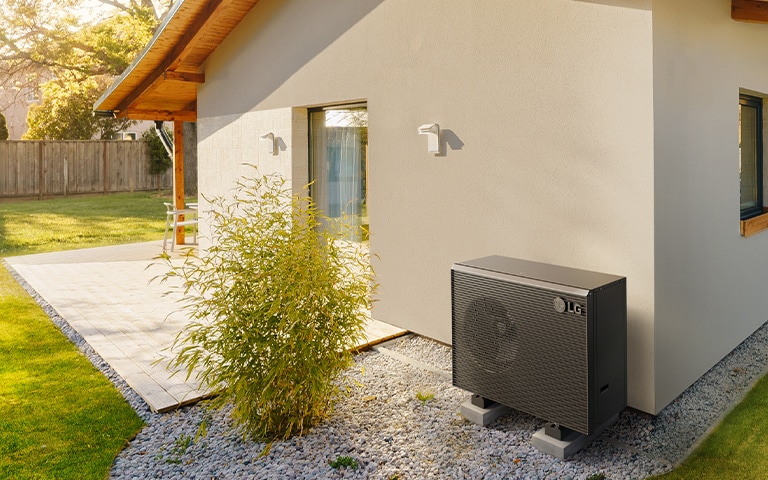 Therma V R290 Pompe à chaleur monobloc installée dans un jardin à côté d'un mur de maison, mettant en valeur son design épuré et sa fonctionnalité.