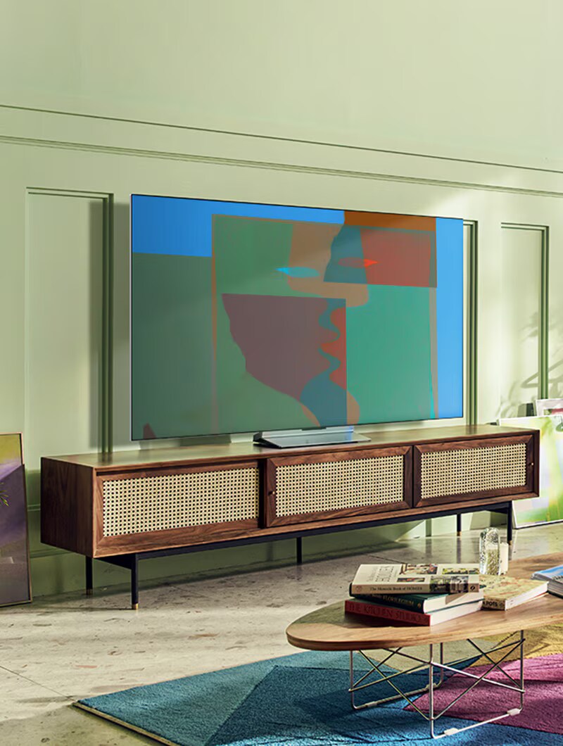 Een LG OLED televisie met draaistandaard staat in een kleurrijke woonkamer met houten meubilair en groen. Een LG OLED televisie met draaistandaard staat in een grijze abstracte kamer.