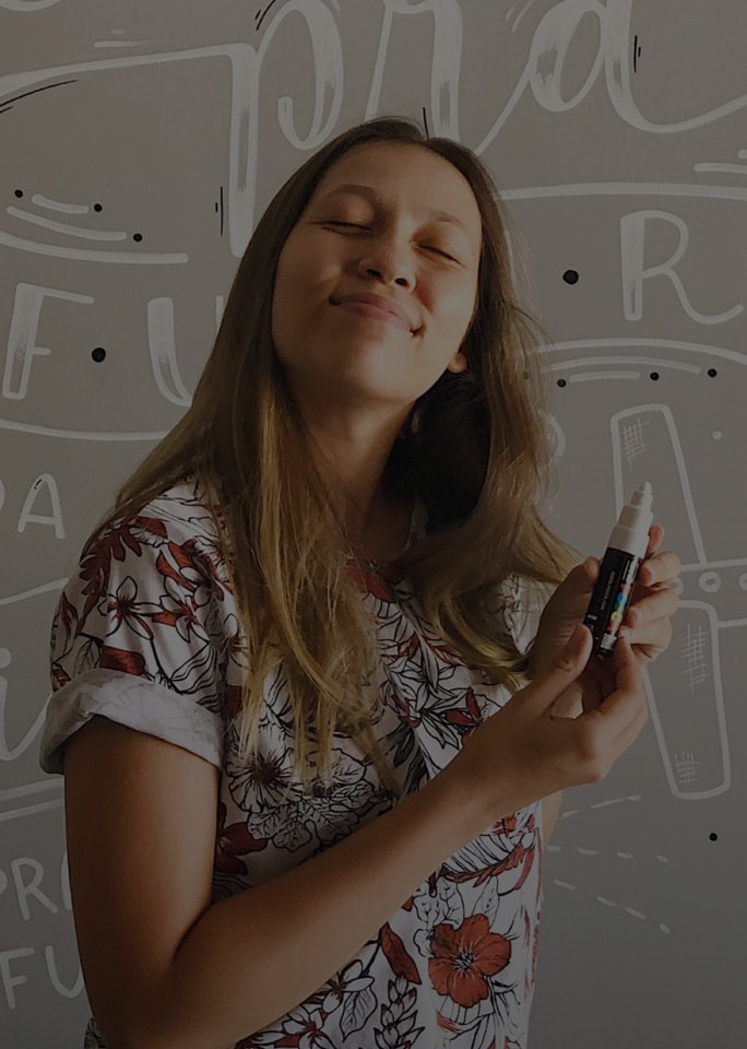 Karol Stefanni sorrindo, segurando uma caneta branca.