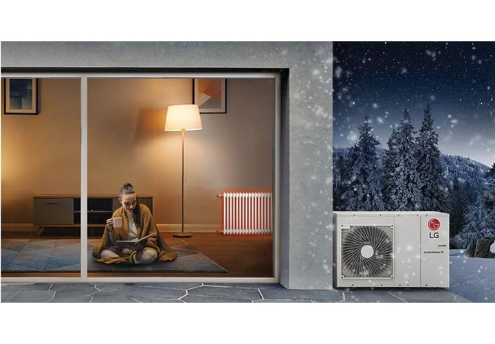 Texto alternativo: Uma mulher relaxa dentro de casa durante uma nevasca à noite, enquanto uma bomba de calor da LG opera com eficiência para manter o ambiente interno aquecido e aconchegante.