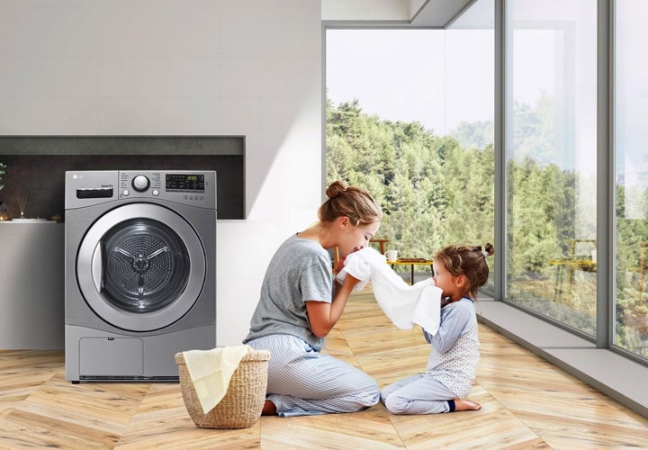 Mãe e filha apreciam o frescor de uma roupa recém-lavada em uma lavadora LG em um ambiente com muita luz natural.