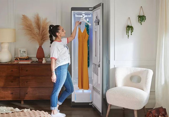 Uma mulher retira um vestido do LG Styler, destacando a forma como o dispositivo ajuda a manter o frescor e a qualidade das roupas.