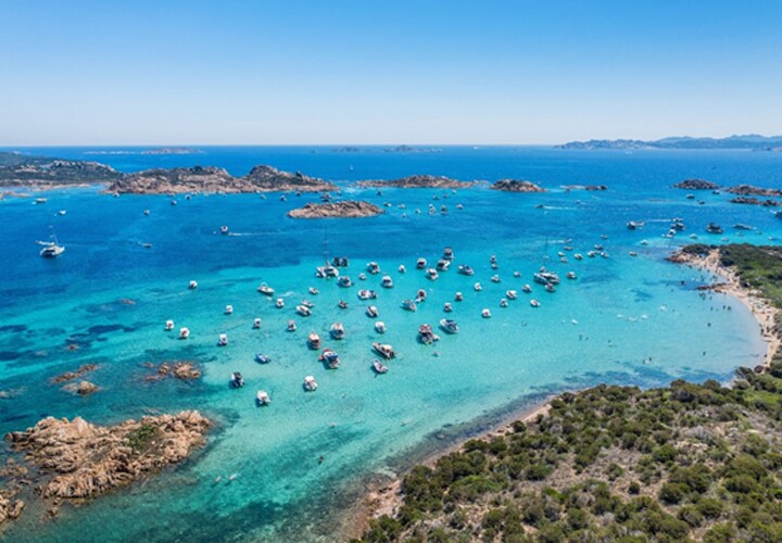 Vista aérea de barcos nas águas cristalinas da costa da Sardenha, ideal para se experimentar com gadgets de camping