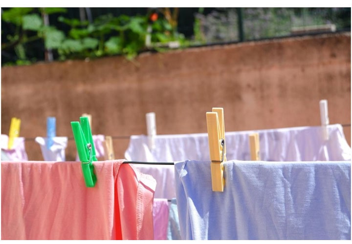 Roupas de várias cores penduradas em um varal com prendedores de plástico.