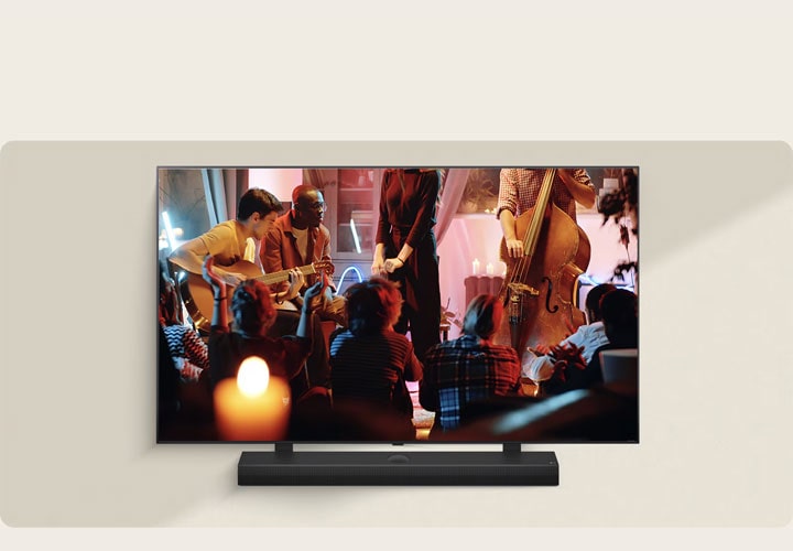 Uma TV LG exibe uma apresentação musical descontraída, com os músicos tocando violão e baixo em um ambiente bem iluminado. Abaixo da TV LG vemos uma soundbar LG, elevando a atmosfera envolvente.