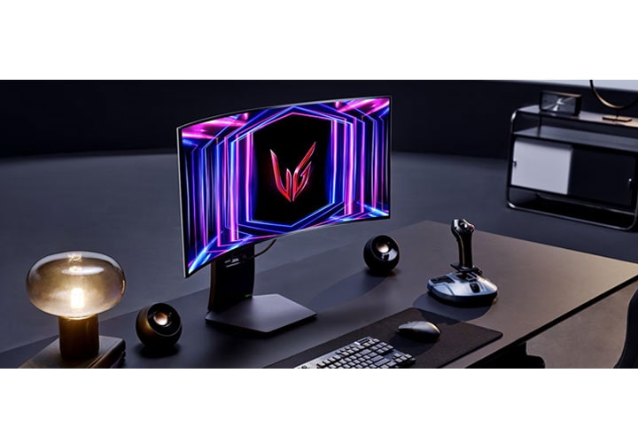 Uma configuração de jogo moderna com um monitor de jogo curvo LG exibindo cores vibrantes, um teclado, mouse, joystick e uma luminária estilosa em uma mesa escura. O fundo apresenta uma unidade de prateleira minimalista.