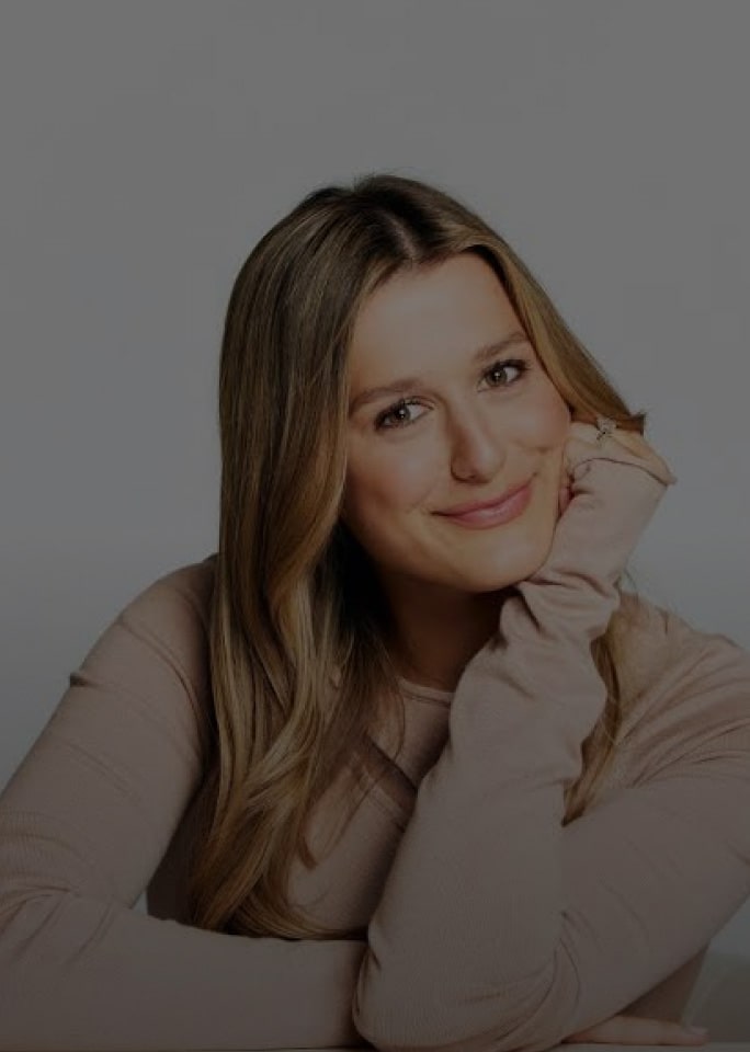 Victoria Browne lächelt sanft und stützt ihr Kinn auf ihre Hand.