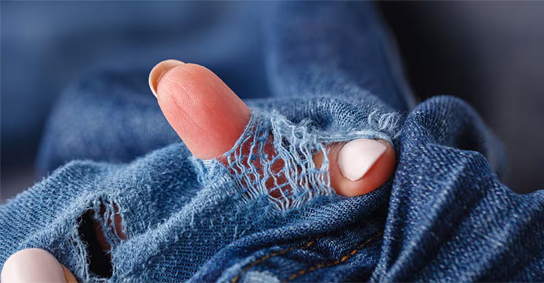 Billede af tøj med hul og finger, der går gennem hullet