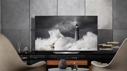 El LG OLED B2 está en una habitación gris con paredes de piedra, accesorios y sillas delante