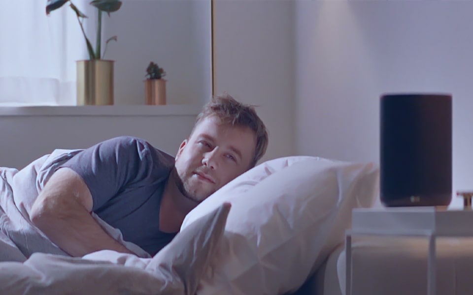 A man waking up and admiring his LG smart speaker