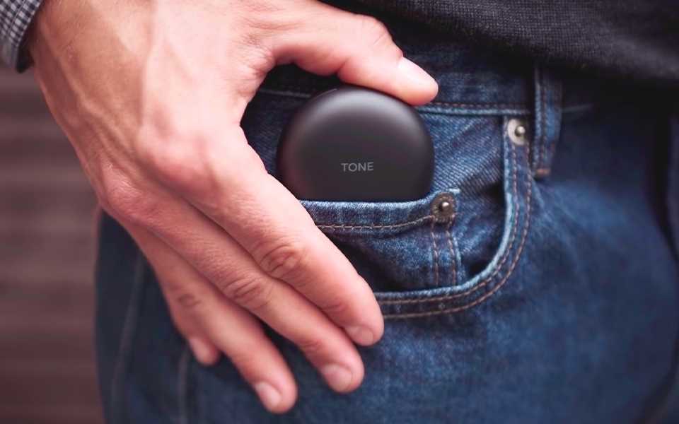 A person placing their LG WIreless earphones into their pocket