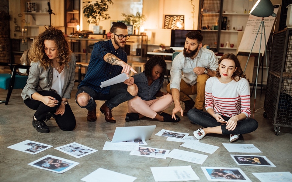 A group of people working together and looking at a papers on the floor