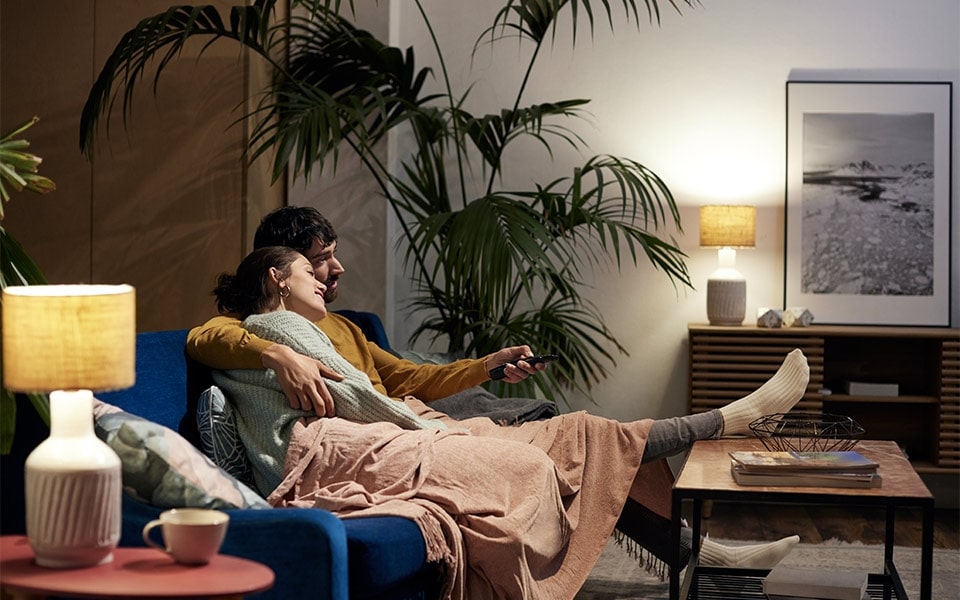 A couple embraces while sitting on the couch and watching their LG TV