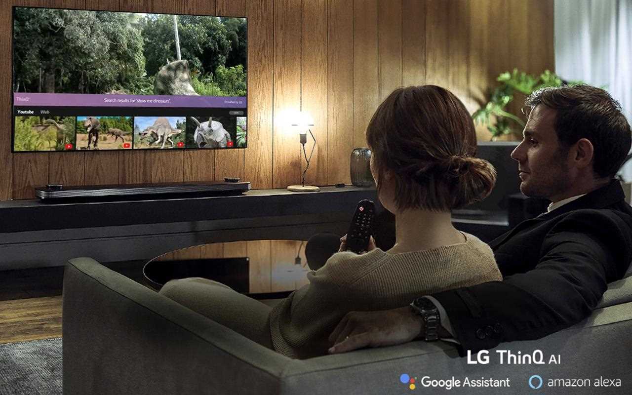 A couple relax as the LG OLED TV helps them choose their favourite photos to display, with the help of Amazon Alexa and the Google Assistant | More at LG MAGAZINE
