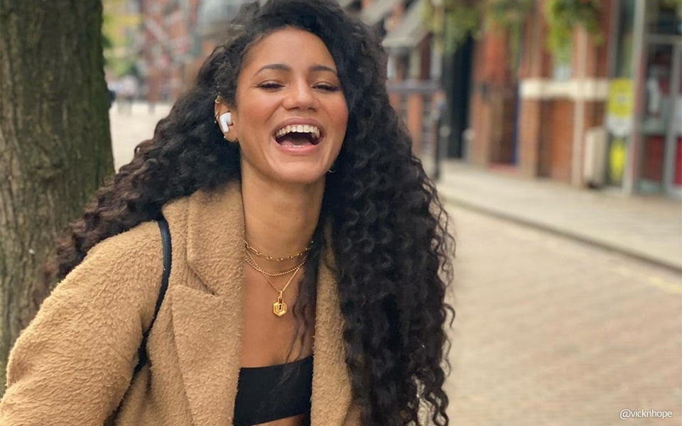 A young woman laughing and wearing a pair of earbuds