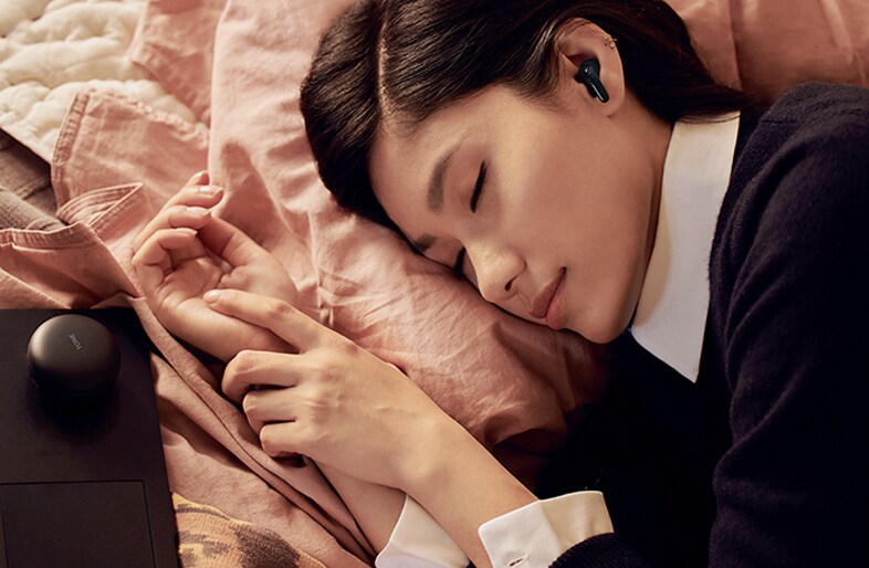 A person is lying in bed sleeping peacefully while wearing T60 earbuds.