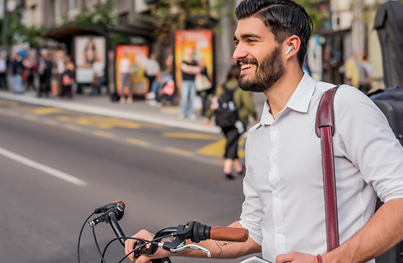 A woman is using the earbuds and holding one in her right hand while whispering into it.