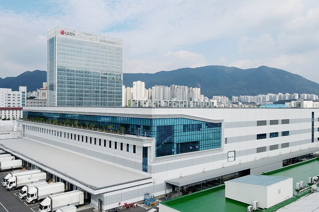 An exterior view of the LG Electronics Changwon Smart Park factory complex with mountains and a cityscape in the background