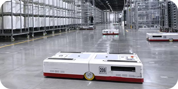 An interior view of the LG Electronics Tennessee Plant, with several automated guided vehicles moving across a large factory floor and tall storage racks and equipment lined up on both sides