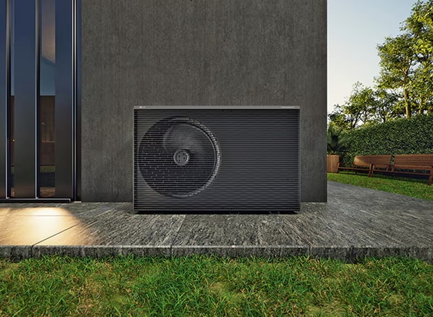 A scene showing a heat pump outdoor unit installed beside a house, illustrating the application of heating and cooling technology designed to reduce the use of substances that affect ozone layer depletion