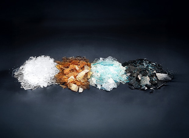 A scene showing different types of raw materials arranged in a row on a dark background, including white, brown, light blue, and black materials, illustrating a diverse range of advanced material compositions