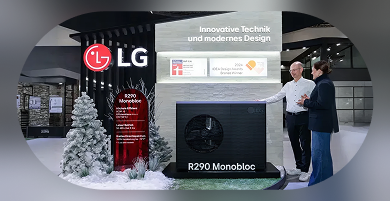 Two people discussing the black R290 Monobloc outdoor unit at an LG exhibition booth. The setup includes a red information board on the left, with the text 'Innovative Technik und modernes Design' and IDEA Design Award logos displayed above the unit.