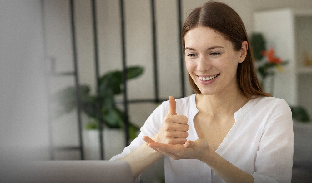 A woman using sign language during an online consultation on a laptop