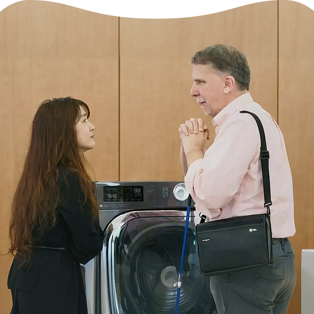 An LG Electronics accessibility advisory group session, where a staff member and a person with a disability discuss usability improvements in front of a washing machine
