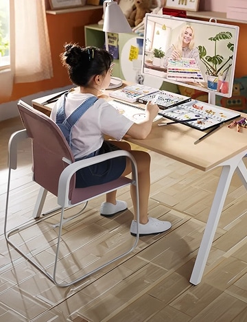 A scene of a child sitting at a desk with art supplies spread out, following a drawing lesson while connected to an instructor on an LG StanbyME screen