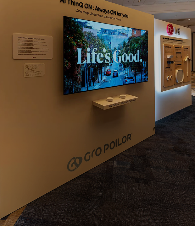 LG Comfort Kit exhibition booth featuring a wall-mounted TV displaying "Life's Good" and smart home accessories.