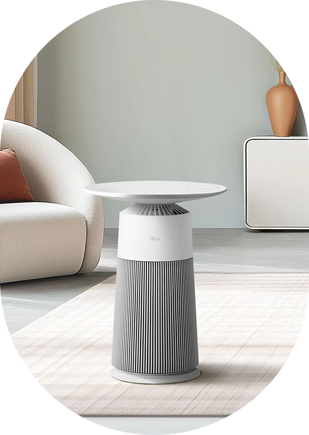 A lifestyle image featuring the LG PuriCare™ Aero Furniture, a table-type air purifier, placed on a rug in a stylish living room
