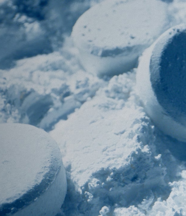 Close-up of circular LG Mineral Wash tablets resting on a bed of fine white powder, illustrating deep cleaning mineral technology.